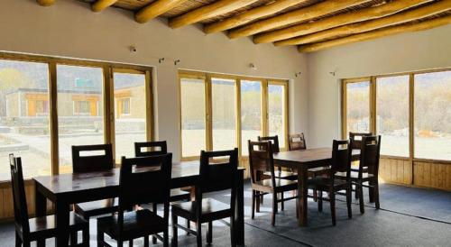 a dining room with tables and chairs and windows at Hunder Tamarix Resort in Hundar