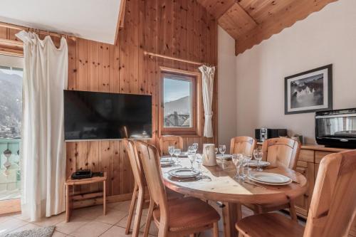 une salle à manger avec une table avec des chaises et une télévision dans l'établissement Appartement Edelweiss, à Saint-Gervais-les-Bains