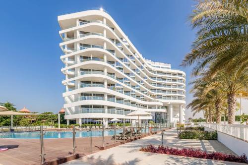 a large white building with a swimming pool and palm trees at GlobalStay Azizi Mina Beachfront Apartments Palm Jumeirah in Dubai