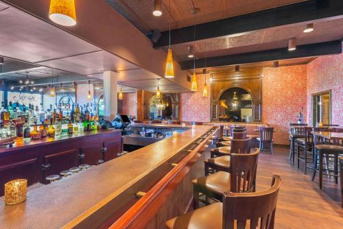 a bar with a long wooden counter and chairs at The Inn at Gran View Ogdensburg, an Ascend Collection Hotel in Ogdensburg