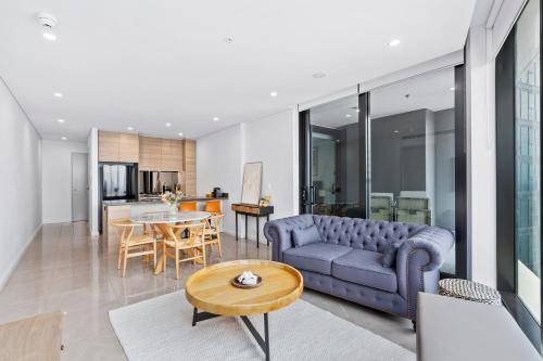 a living room with a blue couch and a table at Surfers Paradise New Beachfront Apartments in Gold Coast