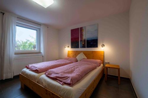a bedroom with a bed with pink sheets and a window at Ferienwohnung am Kurgebiet in Bad Waldsee