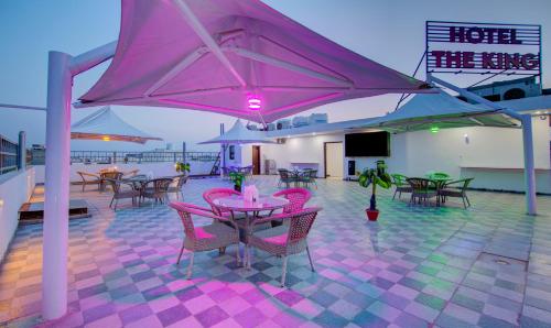 a patio with pink tables and chairs and a tv at Treebo The King Mohali in Mohali