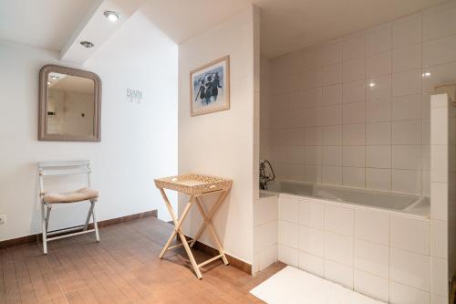 La salle de bains est pourvue d'une baignoire, d'un tabouret et d'un miroir. dans l'établissement Rosa - Sublime villa piscine avec vue et pinèdes, à Saint-Georges-dʼOrques