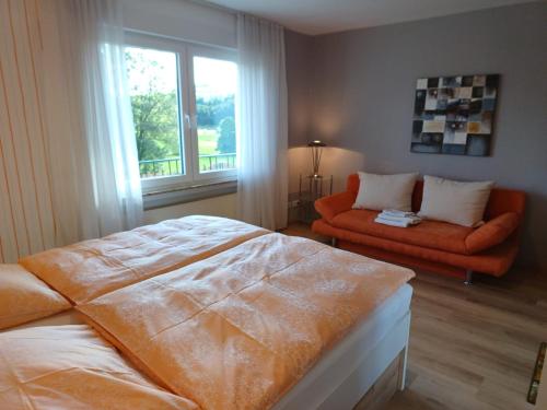 a bedroom with a bed and a couch and a window at Ferienhaus Birkelbach in Erndtebrück