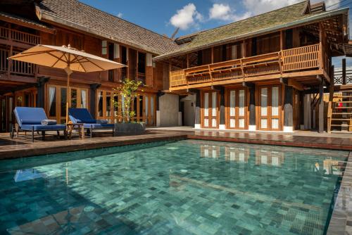 清迈Aleenta Retreat Chiang Mai - The Leading Hotels of the World的一个有两把椅子和一把遮阳伞的游泳池