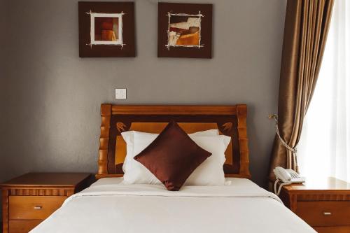 una camera da letto con un letto con lenzuola e cuscini bianchi di Highlands Apartment a Kigali