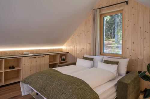 a bedroom with a large white bed and a window at steiRerBLiCke - Wirtsalm Chalets in Pölsen