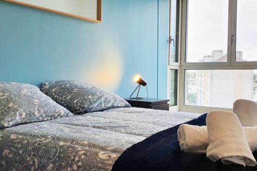 Cet appartement comprend une chambre dotée d'un lit avec un mur bleu et une fenêtre. dans l'établissement Cours de la Rep - 50m Gare et Tram, au Havre