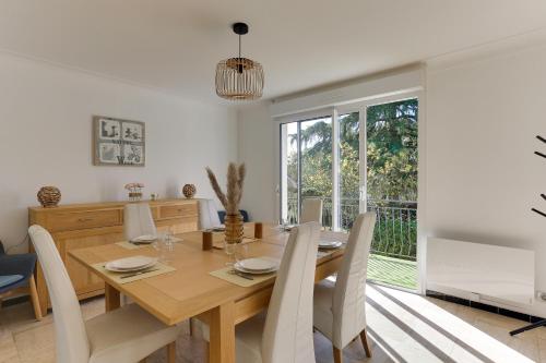 une salle à manger avec une table et des chaises en bois dans l'établissement Arthur - Appt pour 6 avec jardin partagé, à Bruz