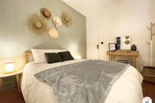 - une chambre dotée d'un grand lit blanc avec des chapeaux au mur dans l'établissement l'Exotique - Vue Pl Vieux Marché - Standing, à Rouen