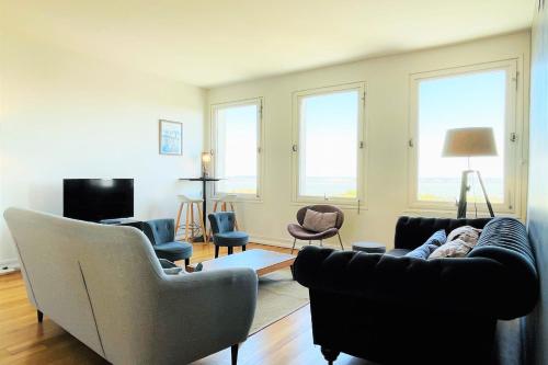 un salon avec un canapé, des chaises et des fenêtres dans l'établissement Vue Baie de Seine - Parking - Pont de Normandie, à Honfleur