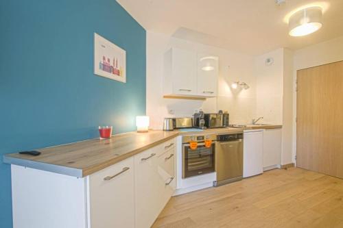 une cuisine avec des armoires blanches et un mur bleu dans l'établissement Port de Plaisance - Balcon - Hypercentre - Coup de cœur, à Caen