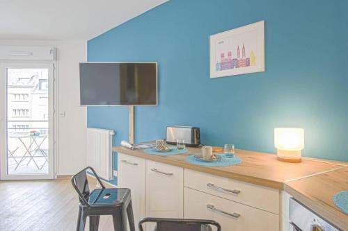 une cuisine avec des murs bleus et une table et des chaises dans l'établissement Port de Plaisance - Balcon - Hypercentre - Coup de cœur, à Caen