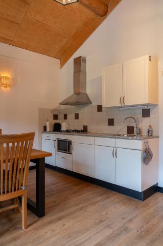 a kitchen with white cabinets and a wooden table at Boomgalows De Roestelberg in Kaatsheuvel