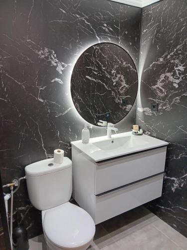 a bathroom with a toilet and a sink and a mirror at Tranquil Oceanfront Escape, One-Bedroom Haven in Mijas