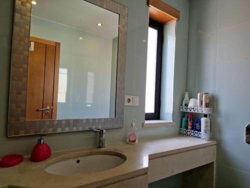 a bathroom with a sink and a large mirror at Apartment T1 60 sq m for rent next to the bay in São Martinho do Porto