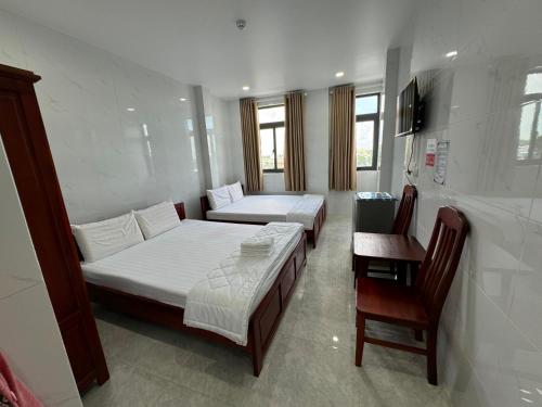 a bedroom with two beds and a table and a chair at Bảo Di Sóc Trăng Hotel in Soc Trang