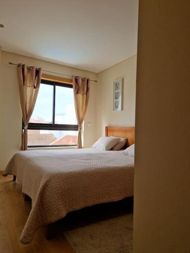 a bedroom with a bed and a large window at Apartment T1 60 sq m for rent next to the bay in São Martinho do Porto