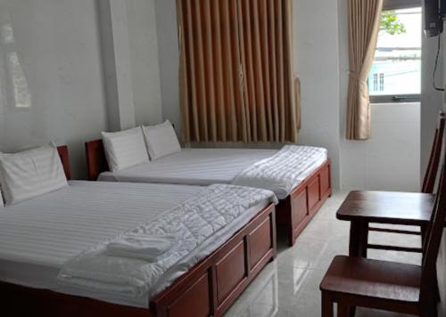 a room with two beds and a table and a window at Bảo Di Sóc Trăng Hotel in Soc Trang