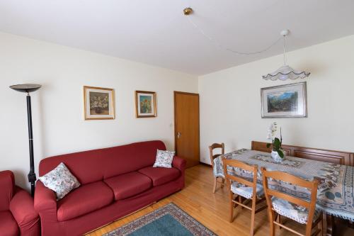 a living room with a red couch and a table at Dolomites Apartment Finestra sul Civetta in Alleghe