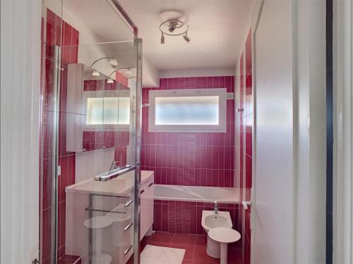 La salle de bains rouge est pourvue de toilettes et d'un lavabo. dans l'établissement Belle terrasse vue mer , proche plages 223L FOV, à Cannes