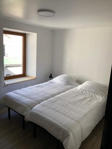 - un lit blanc dans une chambre avec fenêtre dans l'établissement Petit cocon géromois, à Gérardmer