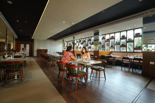 two people sitting at tables in a restaurant at Magnet Hotel in Kannur