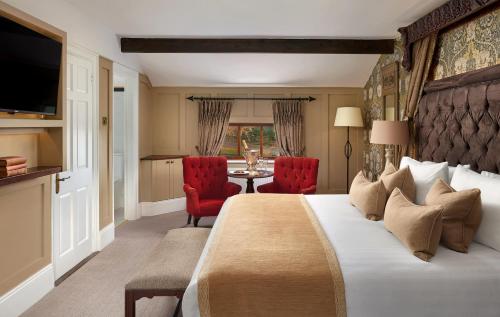 a hotel room with a large bed and two red chairs at Cabra Castle Hotel in Kingscourt
