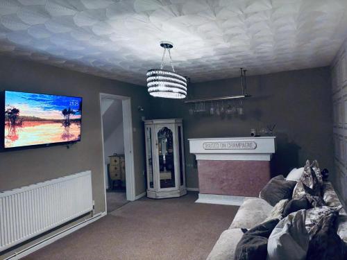 a living room with a couch and a tv on a wall at Modern Lancashire stay with private Hot-tub in Skelmersdale