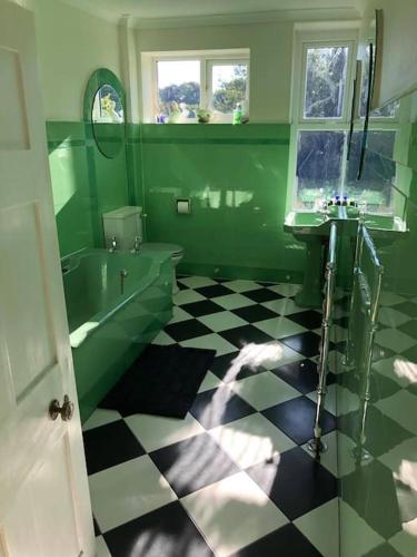 a green bathroom with a black and white checkered floor at Historical Country Retreat with Modern Amenities in Gravesend