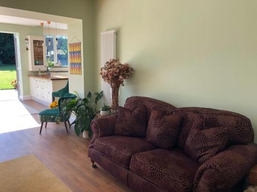 a living room with a brown couch and a kitchen at Historical Country Retreat with Modern Amenities in Gravesend
