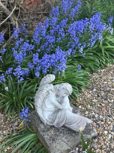 a white angel statue sitting next to blue flowers at Historical Country Retreat with Modern Amenities in Gravesend