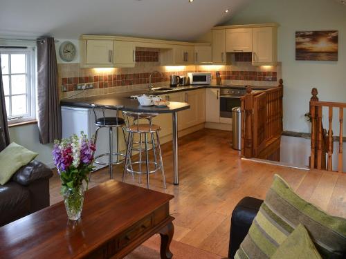 una cucina e un soggiorno con un tavolo e un bancone di April's Cottage a Kilkhampton