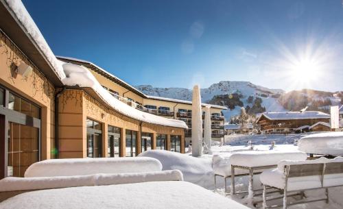 a building covered in snow with tables and chairs at Panoramahotel Oberjoch in Bad Hindelang