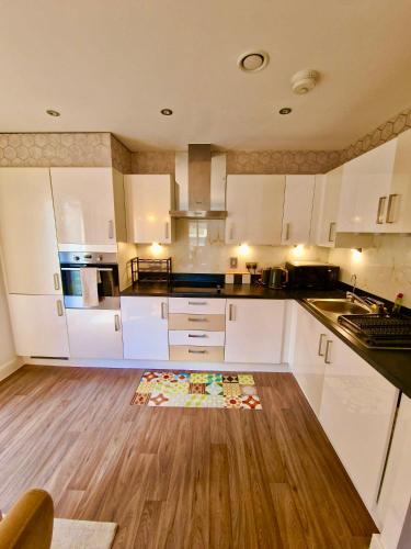 a kitchen with white cabinets and a wooden floor at The Mirrored House in Kent