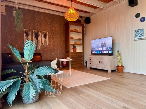 a living room with a couch and a flat screen tv at Guest house with private pool & jacuzzi in Velddriel