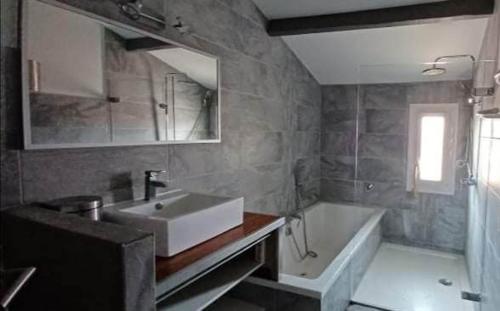 une salle de bain avec un lavabo et une baignoire dans l'établissement Petit appartement 2 chambres avec terasse dans villa grimaude, à Jacou