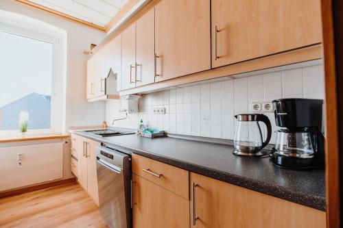 a kitchen with wooden cabinets and a black counter top at Ferienwohnung Oberhausen Sterkrade nahe Westfield CentrO in Oberhausen