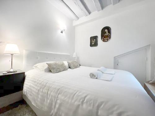 une chambre blanche avec un grand lit blanc avec des oreillers dans l'établissement L'Ecrin: Appartement de charme en cœur historique, à Dijon