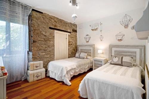 a bedroom with two beds and a stone wall at Regalate Paz in Estallo