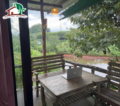 a wooden table with a laptop on top of it at Khlongsaeng farmstay in Ban Ta Khun