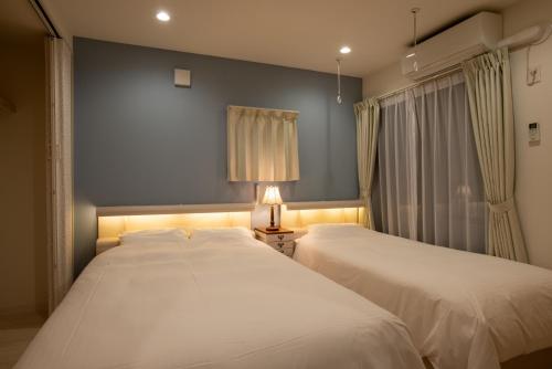 two beds in a bedroom with a lamp and curtains at ローズパーク八番館 in Tokyo