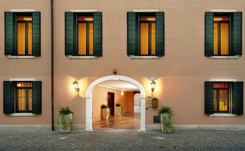 a pink building with an arch and windows at Residence La Fenice in Padova