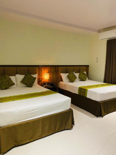 a hotel room with two beds and a window at Maxi Hotel and Event Center in Tagbilaran City