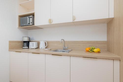 a kitchen counter with a sink and fruit on it at Sun & Beach Apartments Bel Mare with Parking by Noclegi Renters in Międzyzdroje