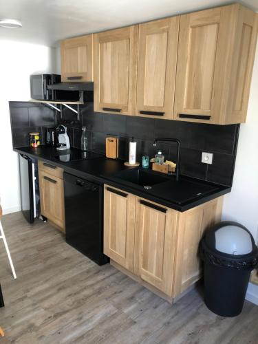 une cuisine avec un comptoir noir et des placards en bois dans l'établissement Petit cocon géromois, à Gérardmer