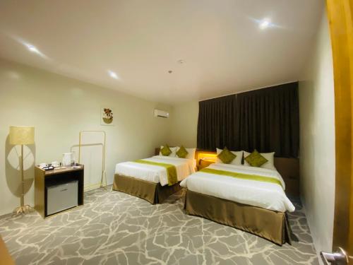 a hotel room with two beds and a lamp at Maxi Hotel and Event Center in Tagbilaran City