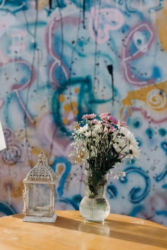 a vase with flowers and a lantern on a table at חאן הכנסת אורחים B''H village שומר שבת in Nevatim