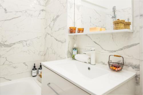 une salle de bain blanche avec un lavabo et un miroir dans l'établissement 5mn Monaco - Cosy 2 pièces - Balcon vue mer - CL, à Beausoleil